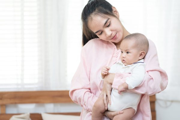 family, child and parenthood concept – happy beautiful young asi family, child and parenthood concept - happy beautiful young asian mother smiling hugging holding newborn baby in her arms at home. Mother’s day banner with copy space for advertise