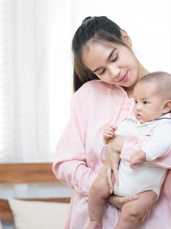 family, child and parenthood concept – happy beautiful young asi family, child and parenthood concept - happy beautiful young asian mother smiling hugging holding newborn baby in her arms at home. Mother’s day banner with copy space for advertise